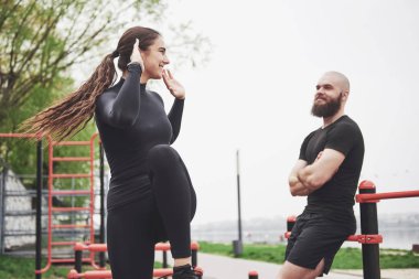 Young man and woman perform exercises and stretch marks before doing sports.