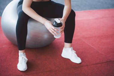 Eğitimden sonra dinleniyorum. Spor salonunda egzersiz minderinde otururken güzel genç bir kadının manzarasını kapat..