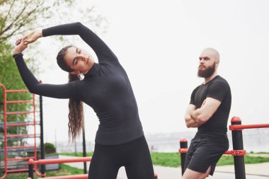 Young man and woman perform exercises and stretch marks before doing sports.