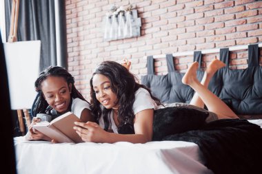 İki güzel afrikalı kız uykusunda gülümsüyor ve güneşli bir günde sabah uyandılar. Kadınlar kitabı okur ve iletişim kurarlar.