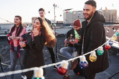 Parti gebeliği. Çatıdaki her yerde ampuller var. Genç arkadaşlar hafta sonlarını gitar ve alkolle geçirmeye karar verdiler..