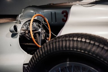 Yan, gri retro spor coupe Cabriolet iç ve kaput yakın görünüm: ahşap direksiyon, gösterge paneli, ayna, alaşım diskler ve arka planda klasik araba.