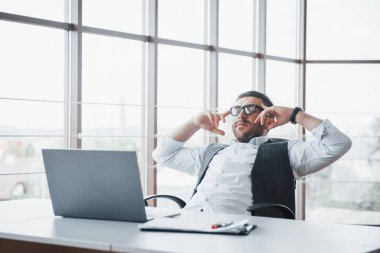 İşçi, ofisinde dizüstü bilgisayarı olan genç bir adam..