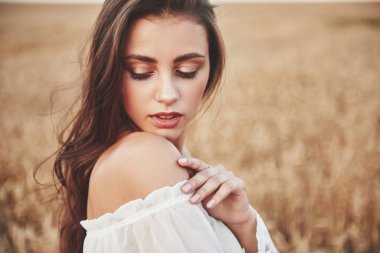 Buğday tarlasında bulunan uzun saçlı mutlu bir kadının portresi..