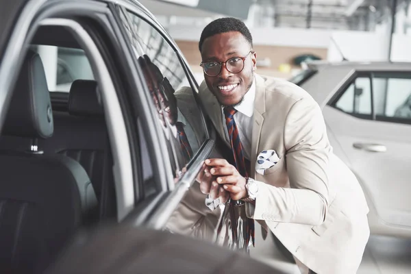 Bonito Homem Negro Concessionária Está Abraçando Seu Carro Novo Sorrindo — Fotografia de Stock