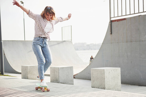 A young sports woman who rides in a park on a skateboard