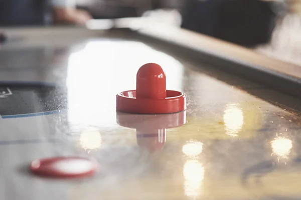 Air hockey table with window lighting and red toy hockey stick.