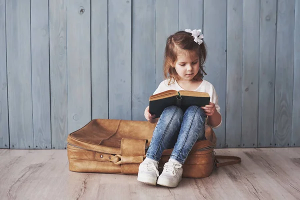 准备好了大旅行 快乐的小女孩拿着一个大手提箱 笑着看有趣的书 自由和想象力概念 — 图库照片