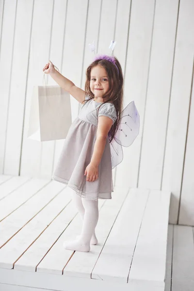 荷物を持ってる美しいです小さな女の子とともに妖精衣装楽しいですポーズのために写真 — ストック写真