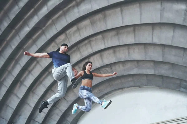 Young happy sports couple in the city street, performing parkour