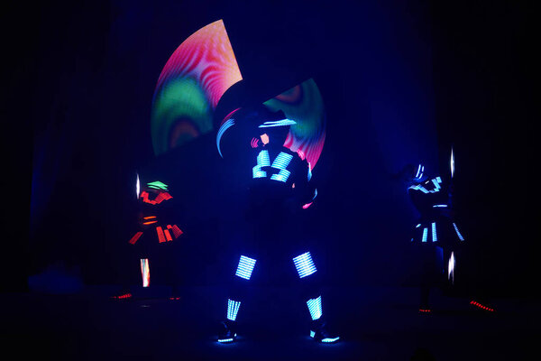 Laser show performance, dancers in led suits with LED lamp, very beautiful night club performance, party.