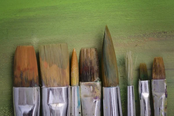 Paint brushes, palette and artwork