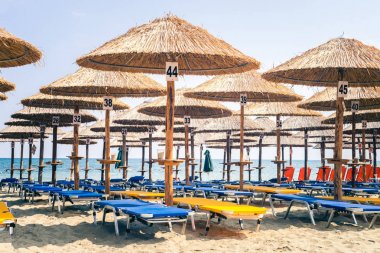 Plajda şemsiye, T bakan altında boş şezlong şezlonglar