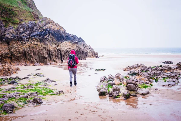 Mujer caminando en la playa rocosa en la bahía de Rhossili, Walesh Coast P — Foto de Stock