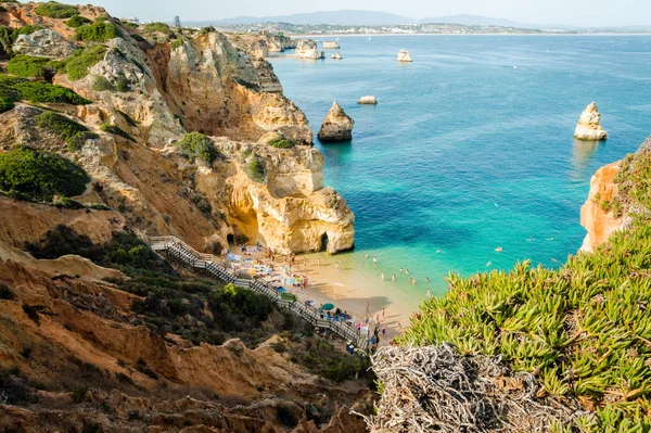 Camilo Beach w Lagos, Algarve, Portugalia. Drobny tajnych plaży między ścianami z wapienia. 200 drewniane schody osłoniętych, piaszczysta Zatoka podzielona przez skały kolorze ochry z rąk wykopał tunelu. — Zdjęcie stockowe