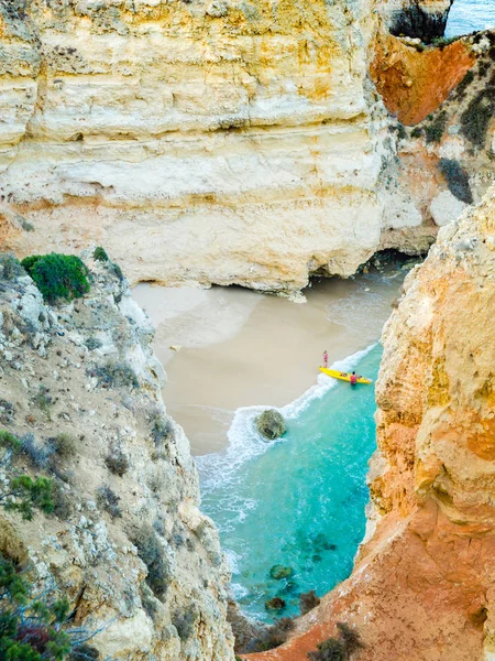 Kleine afgelegen strand in Lagos, Algarve, Portugal. Een verborgen geheime strand tussen kalkstenen muren. Mensen met een gele kajak een bezoek aan het strand. — Stockfoto