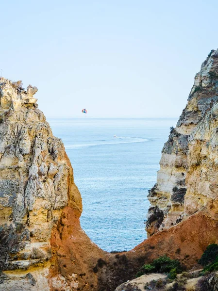 Parasailing, también conocido como parasending o parakiting en las costas del Algarve en Lagos, Portugal. Rodeado de calizas amarillas y anaranjadas . — Foto de Stock