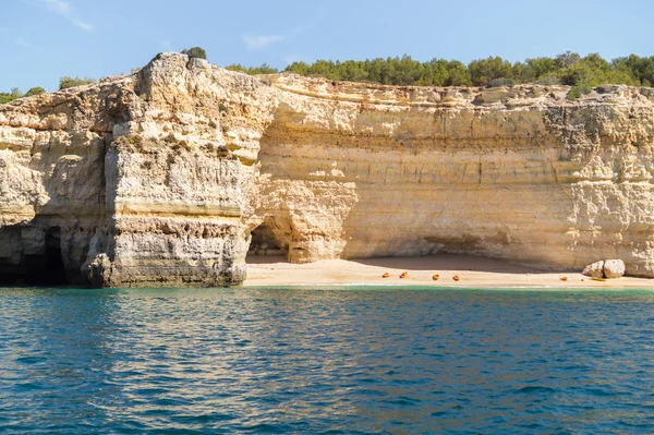 Ukryta plaża zdalnego pokryte wapiennych ścianach. Kajak po lewej stronie na plaży przez turystów udał się do zwiedzania jaskini. Algarve, Portugalia — Zdjęcie stockowe