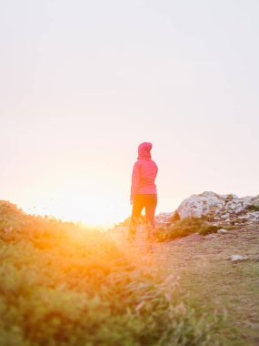 Gün batımında Pembrokeshire Sahil Yolu 'nun tepesindeki bir patikada gün batımında Martin' in Cenneti Pembrokeshire, Batı Galler 'de yürüyen bir kadın..