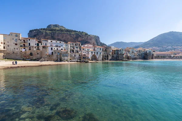 Idyllic view of turquoise sea and houses with Rocca di Cefalu rocky mountain in the background seen from historical old port of Cefalu - Sicily, Italy