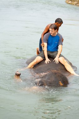Erkek turist fil binmek nehir Nepal sular altında.