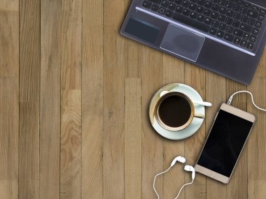 Dizüstü bilgisayar, akıllı telefon ve ahşap zemin üzerine kahve.