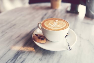 Bir fincan sıcak kahve (sütlü) tablo üzerinde yumuşak odak.