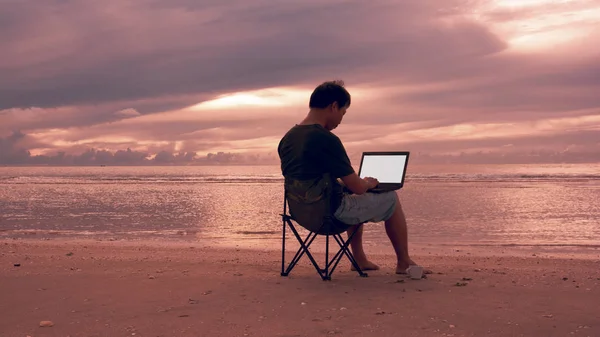 Un homme utilisant un ordinateur portable sur la plage . — Photo