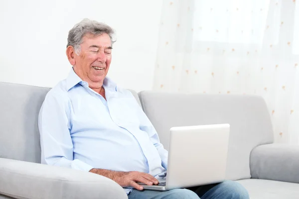 Взрослый человек улыбается во время использования ноутбука — стоковое фото