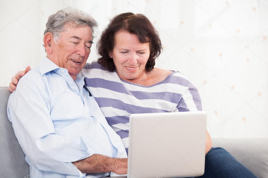 Daughter and father laughing while using laptop