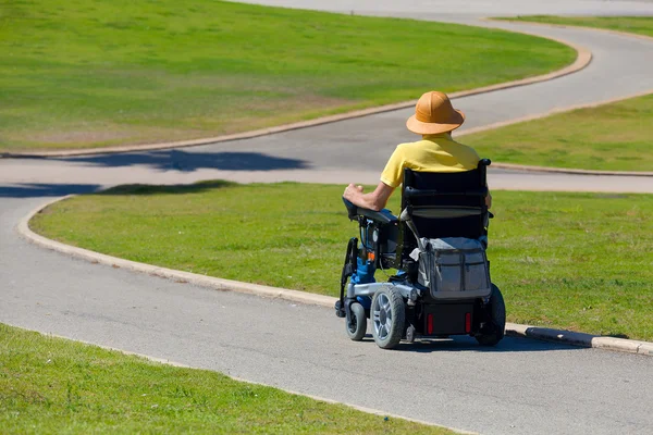 Инвалид в инвалидной коляске наслаждается свежим воздухом в парке — стоковое фото