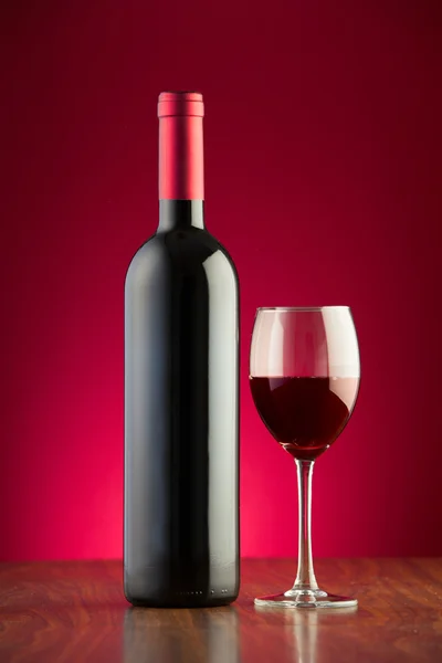 병 및 유리 빨간색 배경 위에 레드 와인의 전체 — 스톡 사진