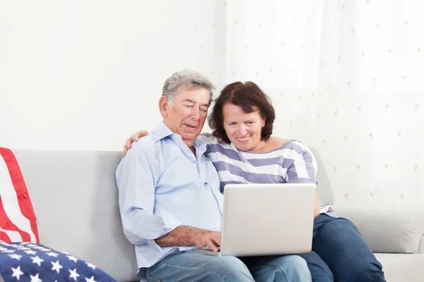 Старшая пара смеется во время использования ноутбука — стоковое фото