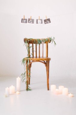 yeşil bitki ve mum ışık arka duvarda asılı bebek resimleri ile dekore edilmiş ahşap sandalye