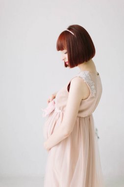 profil görünümü mutlu hamile kadın ayakta tutan pembe ayakkabı bebek için