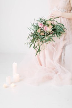 hamile kadın büyük buket çiçek mum ile beyaz arka plan üzerinde sandalye üzerinde oturan kırpma