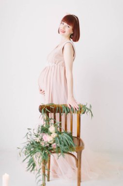 hamile kadının katta dekore edilmiş sandalye beyaz mumlar yanan ile ayakta tam uzunlukta 