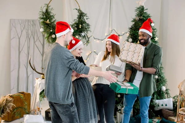 행복 한 웃음과 아름 다운 아늑한 스튜디오에서 크리스마스 선물을 공유 하는 친구의 그룹 — 스톡 사진
