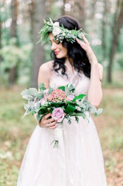 Doğada gelinlik giymiş, başında yeşil bir çelenk olan gelin. Çam ormanında güzel sanatlar tarzında fotoğraf çekimi..