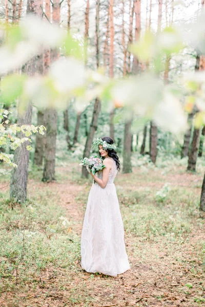 Belle fabuleuse mariée brune heureuse avec bouquet élégant et couronne sur le fond de la forêt verte — Photo