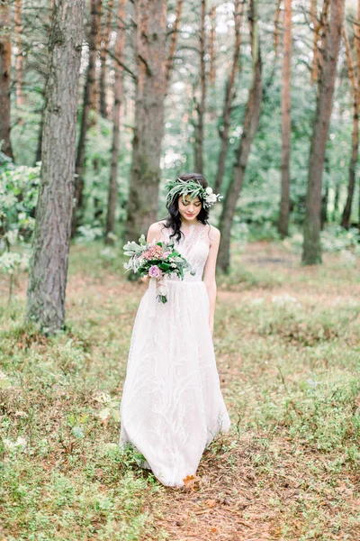 Vue complète de la mariée souriante dans la robe de mariée marchant dans la forêt verte . — Photo