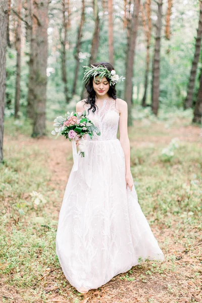 Vue complète de la mariée souriante dans la robe de mariée marchant dans la forêt verte . — Photo