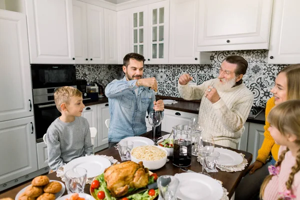 Beautiful happy family celebrating thanksgiving day together. Father opens a bottle of red wine, grandfather is laughing — Stock Photo, Image