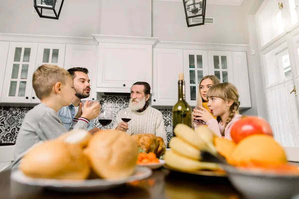 Family With Grandfather Enjoying Thanksgiving Meal At Table. Happy large family having holiday dinner together at kitchen