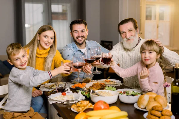 家庭共进晚餐庆祝概念，感恩节假期。 一家人幸福地坐在桌旁笑着，享受着在一起的时光，享用着美味的晚餐，手里拿着酒杯和果汁 — 图库照片