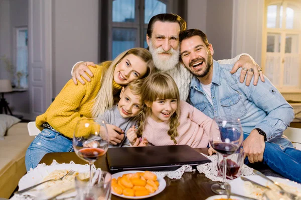 Mom, dad and their little children, grandfather have holiday dinner , sitting at the table in cozy room, using laptop and talk. Happy family concept. — Stock Photo, Image