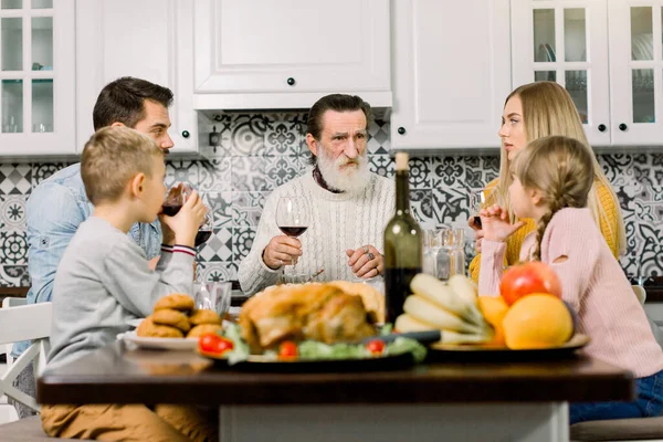 Vícegenerační šťastná rodina pozvedne sklenice, aby pronesla přípitek u svého stolu na Díkůvzdání. Dědeček, rodiče a děti spolu večeří — Stock fotografie