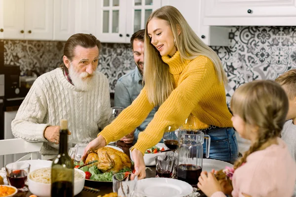 兴奋美丽的家庭看着感恩节的火鸡。 年轻女人拿着烤鸡或火鸡的盘子 — 图库照片