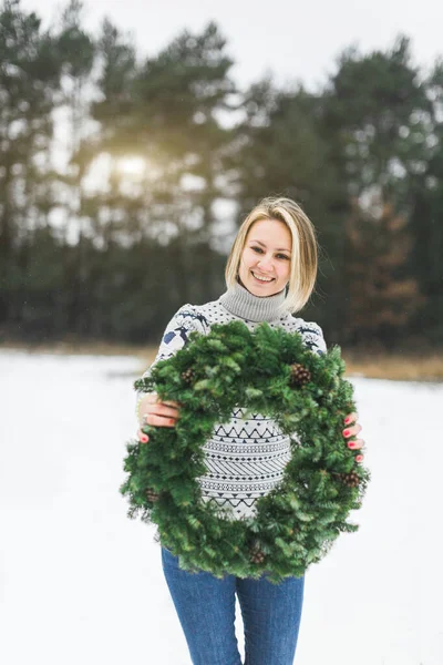 Jeune jolie fille tenant une couronne de Noël faite par elle-même à l'extérieur. Concept de Noël. humeur de Noël — Photo