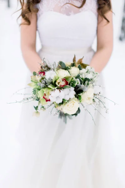 Ramo de boda con flores y algodón en las manos de la novia. Invierno, bosque nevado. Imagen recortada —  Fotos de Stock